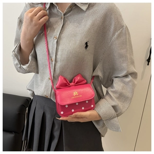 Détail d'un mini sac bandoulière avec nœud rose et motif à pois blancs élégant