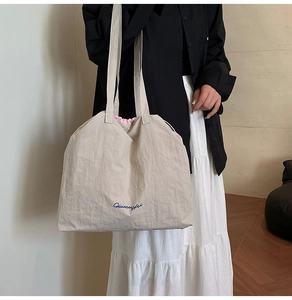 Détail du grand sac cabas en nylon beige avec broderie bleue et doublure rose