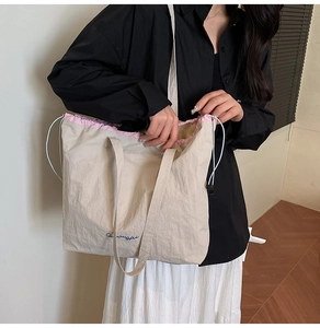 Model showing side view of beige canvas tote with pink trim and drawstring closure