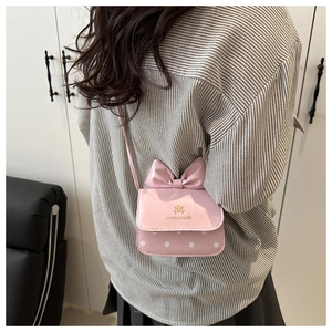 Sac bandoulière rose avec nœud et pois blancs porté par un mannequin femme