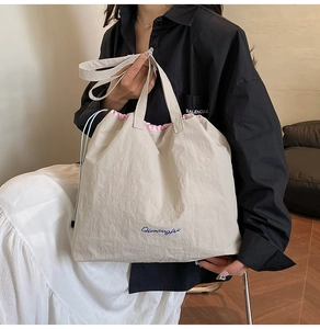 Détail du sac cabas blanc cassé à cordon avec broderie bleue et doublure rose vif