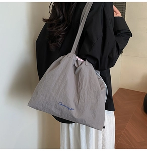 Détail du sac cabas en nylon gris avec cordon de serrage et broderie Qiwangfi bleue