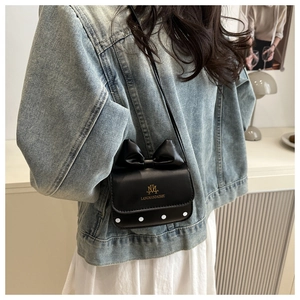 Détail d'un mini sac à bandoulière noir avec un nœud et des pois blancs sur la base
