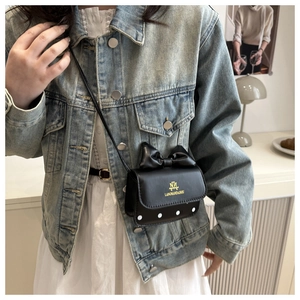 Détail du mini sac bandoulière noir avec un grand nœud et des motifs à pois blancs