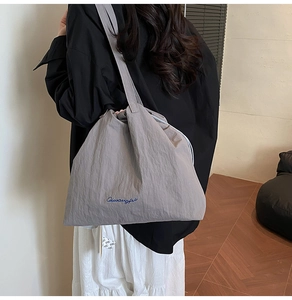 Detail of dark grey drawstring tote bag with blue typography on a high-density fabric