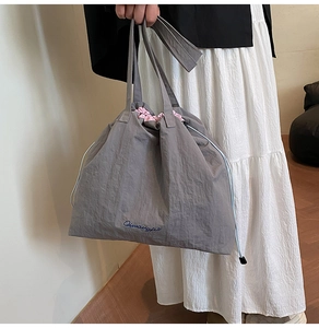 Close-up of grey drawstring tote bag featuring nylon texture and pink lining detail