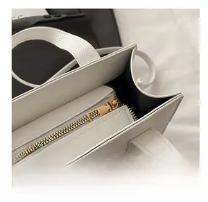Gros plan sur la fermeture éclair dorée et le cuir grainé de ce sac cabas blanc chic
