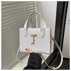 Détail du sac blanc texturé avec pendentif cerf doré et finitions métalliques élégantes