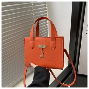 Détail du sac cabas orange en cuir grainé avec pendentif cerf doré et fermoir chic