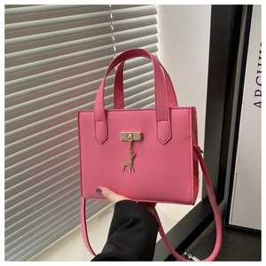 Détail d'un cabas rose en cuir grainé avec finitions dorées et petit pendentif en cerf