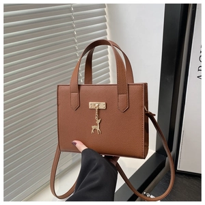 Gros plan du sac cabas marron texturé avec pendentif cerf doré élégant et raffiné
