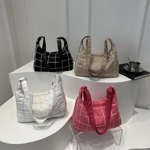 Quilted tote bags in black, khaki, white, and pink on a stylish urban display stand