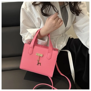 Détail du sac bandoulière rose avec texture croisée et pendentif cerf doré