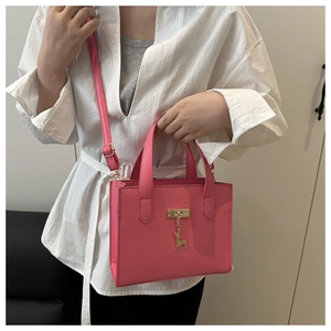 Détail du sac cabas rose avec texture litchi et pendentif cerf doré élégant