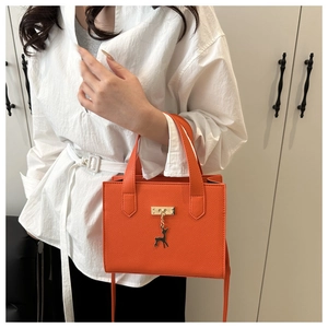 Détail du sac à main carré orange avec pendentif cerf doré et fermoir en métal