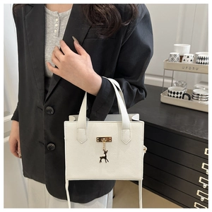 Détails d'un sac blanc en cuir grainé avec fermoir doré et pendentif cerf élégant