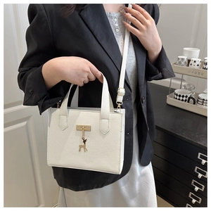 Détail d'un sac à main blanc en cuir grainé avec pendentif cerf doré et poignée élégante