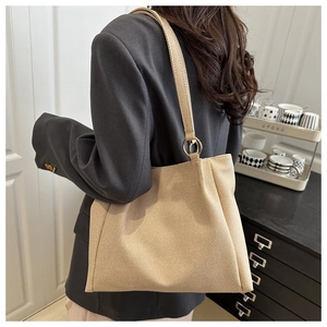 Detail of beige canvas tote bag showing the golden metal ring handle attachment