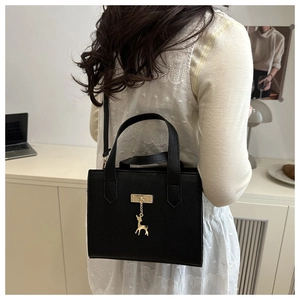 Détail du sac bandoulière en cuir noir avec un pendentif en forme de cerf doré