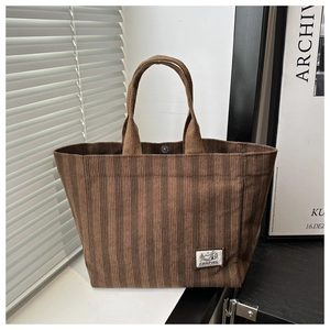 Detailed shot of dark brown corduroy tote bag with camping patch and sturdy handles
