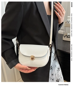 Close-up of white lychee pattern leather handbag with gold round buckle worn by a model