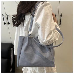 Blue-grey canvas tote bag with gold metal rings shown on model in a modern interior