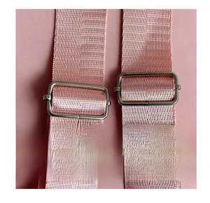 Detail of adjustable pink woven shoulder strap with silver metal buckles on a backpack