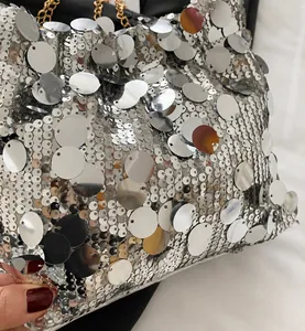 Detail of silver sequin square bag showing metallic texture and golden chain strap