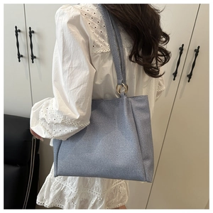 Blue denim tote bag with gold ring handles shown from a model back view perspective