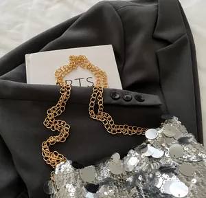 Detail of silver sequin crossbody bag featuring a premium gold double metal chain strap