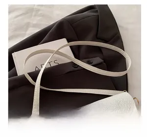 Detail of adjustable strap and gold hardware on white pebble leather shoulder bag