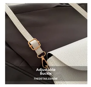 Close-up of white lychee leather texture and golden adjustment buckle on shoulder bag