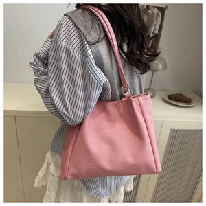 Close-up of pink canvas tote bag with woven texture and gold metal ring strap attachment
