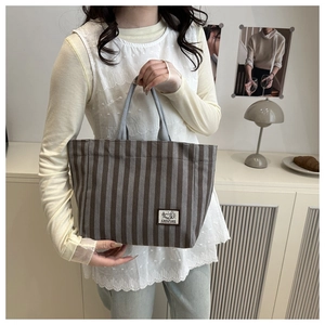 Detailed shot of corduroy tote bag featuring vertical stripes and camping badge patch