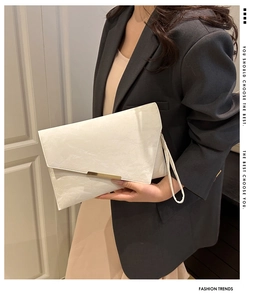 Détail de la pochette enveloppe blanche en cuir texturé avec boucle en métal doré chic