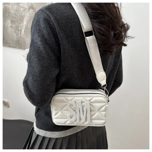 Detailed back view of white quilted crossbody camera bag with SM logo and wide strap