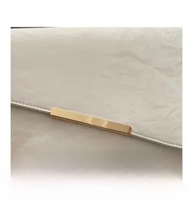 Détail du cuir gaufré blanc avec garnitures métalliques dorées sur la pochette chic