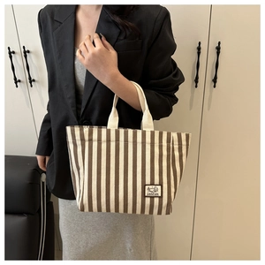 Close-up of striped canvas tote bag with Camping label and durable webbing handles