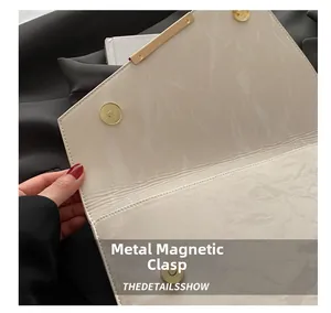 Détail du sac enveloppe marbre blanc avec deux fermoirs magnétiques dorés pour fermeture