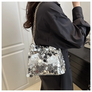 Close-up of silver sequin handbag with gold chain strap on a black shirt