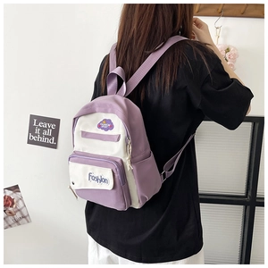 Detail of mini backpack in purple and white contrast with embroidered Fashion patch