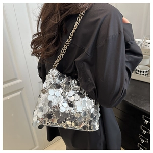 Detail of silver sequin shoulder bag with dual gold chain straps on a model
