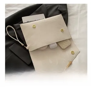 Détail d'une pochette enveloppe crème montrant le rangement pour téléphone et maquillage