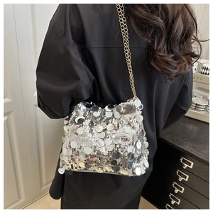 Detailed view of silver sequin crossbody bag with gold chain strap on model