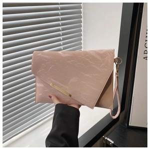 Detail of light pink wrinkled envelope clutch bag with gold metal trim and wrist strap