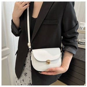 Close-up of white lychee pattern leather saddle bag with golden metal buckle clasp