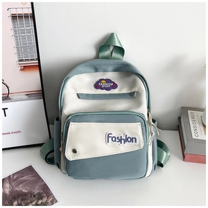 Detail of light green and beige nylon backpack with front zipper pocket and side mesh pouch