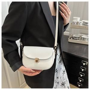 Close-up of white lychee texture saddle bag with golden lock and adjustable strap