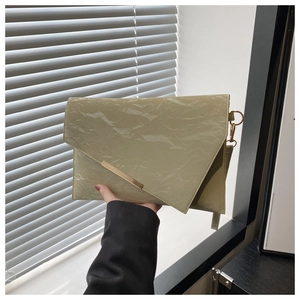 Detailed view of light green pleated envelope bag with elegant gold metal accent bar
