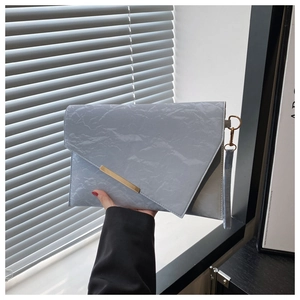 Detail of light blue wrinkled fabric envelope clutch bag with gold metal hardware